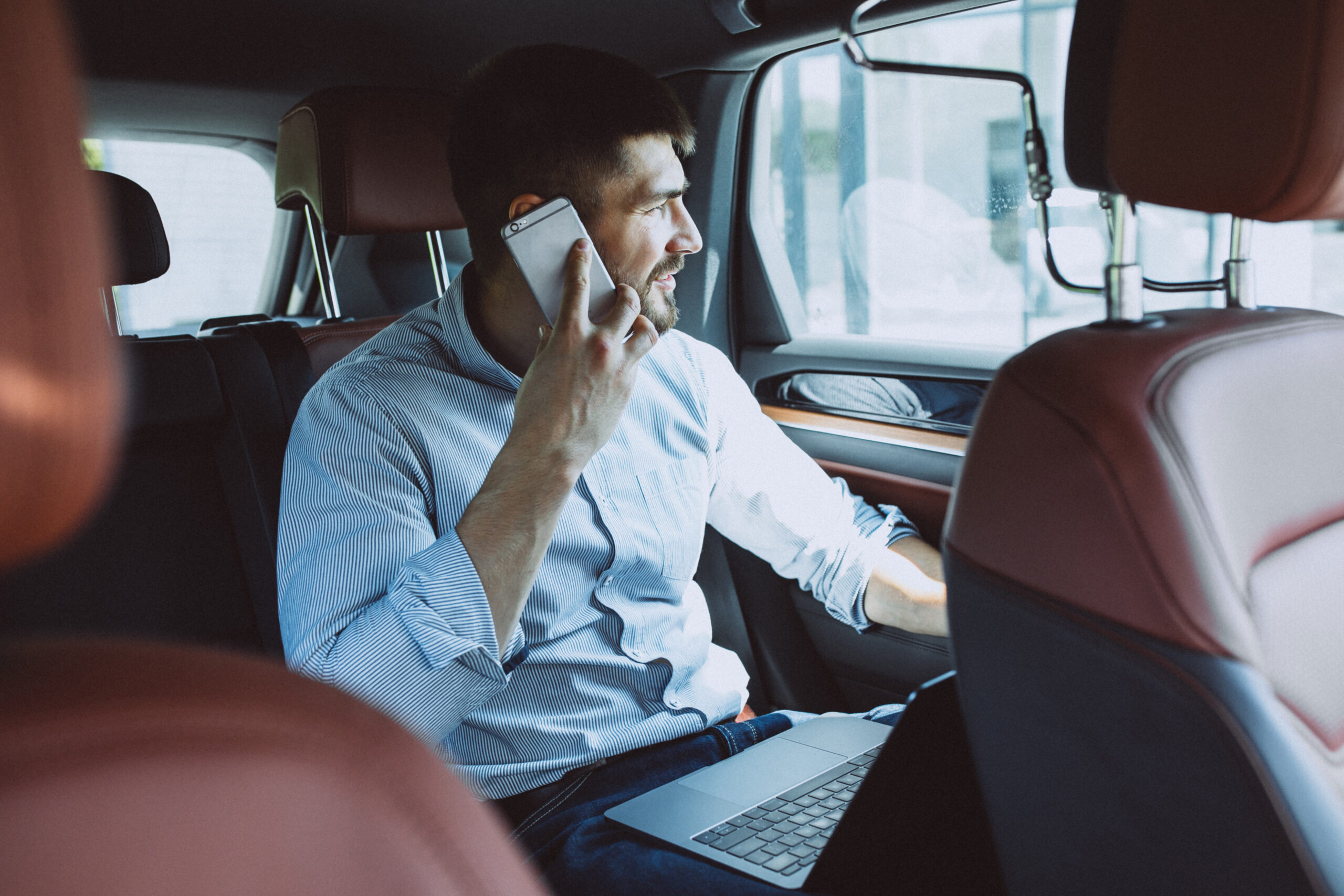 Handsome business man working on a computer in car