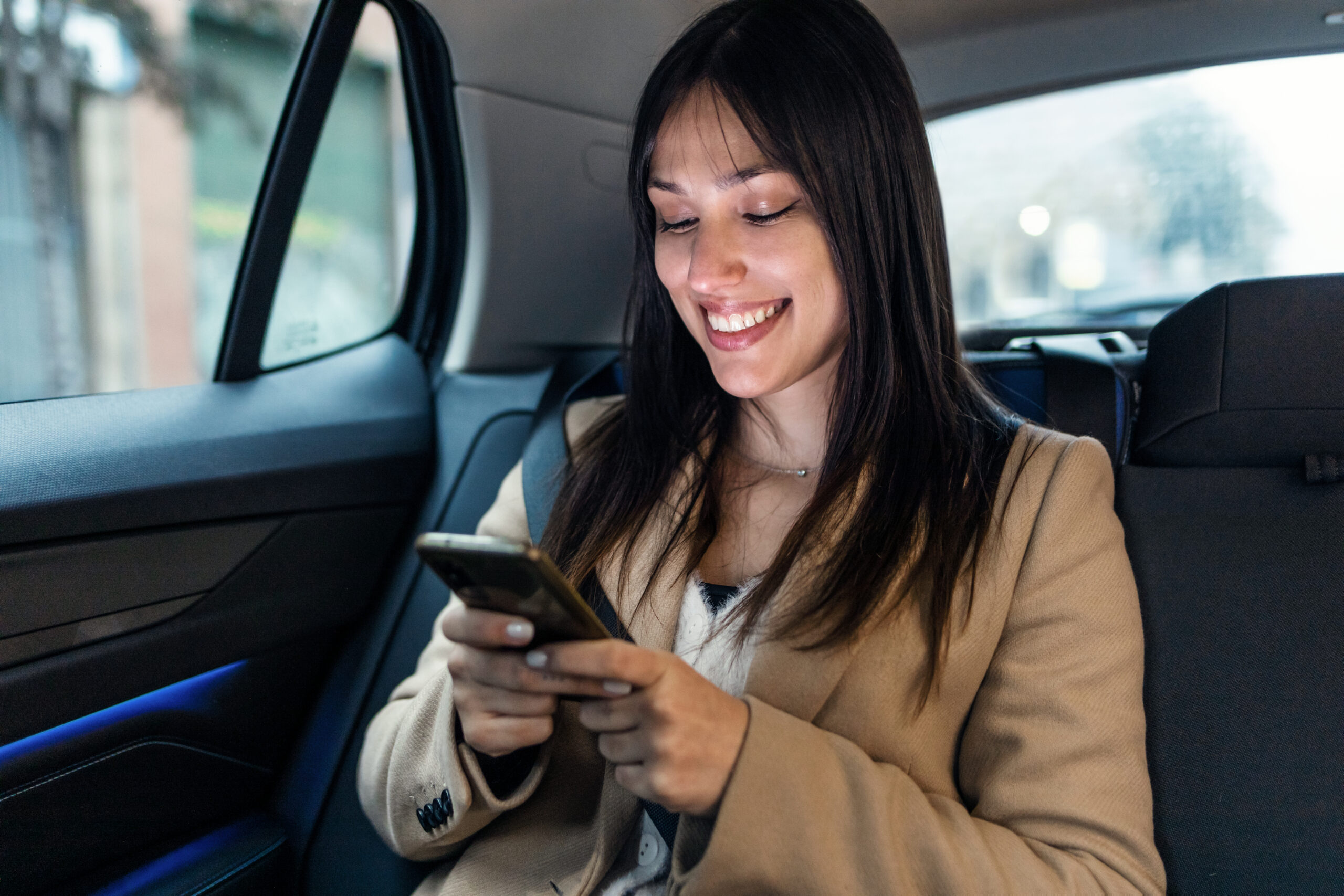 Beautiful young woman sending messages with her mobile phone in